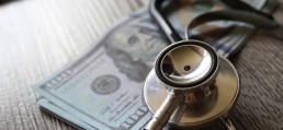 Stethoscope and money on wooden table